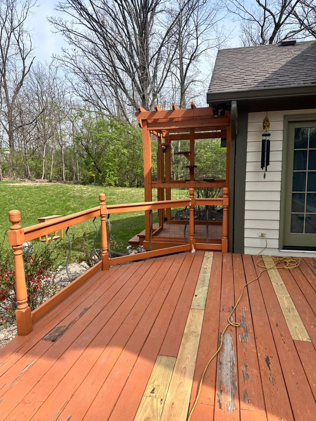 Terraza de madera con barandal y pérgola adosada a casa blanca