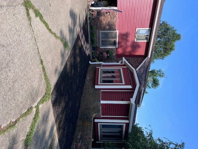 Red building exterior with white trim next to cracked concrete driveway