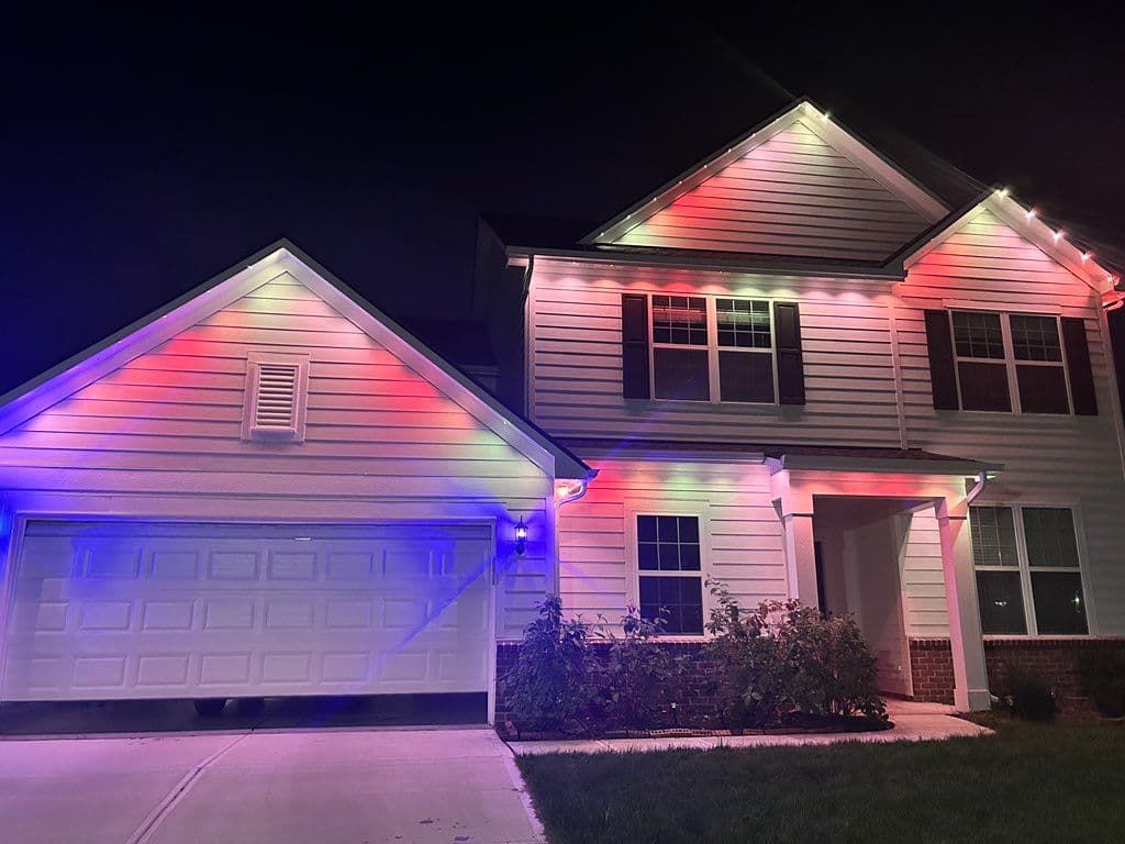 RGB LED soffit lights installed along roofline of two-story house at night