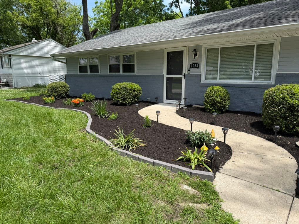 Front yard bed freshly mulched with trimmed shrubs and landscape lights